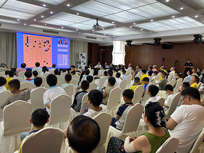 図3：会場では王汝南八段（79歳）と王祥雲四段（35歳）による大盤解説が行われ、多くの地元ファンが耳を傾けた。